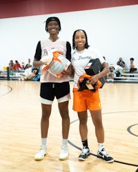 two women standing next to each other on a basketball court