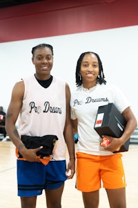 two young women standing next to each other on a basketball court